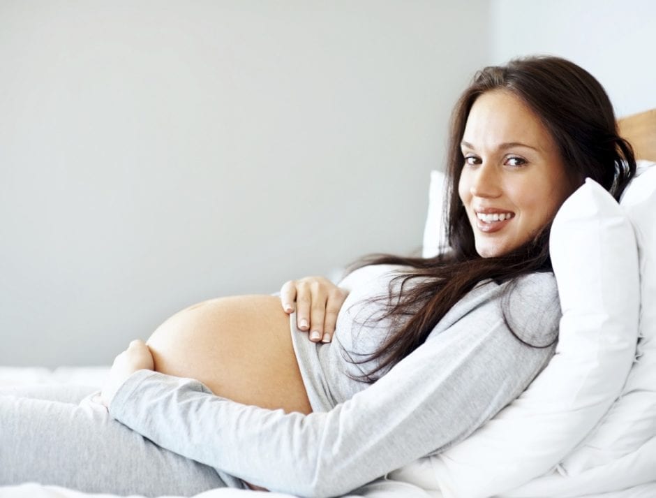 pregnant woman in bed smiling