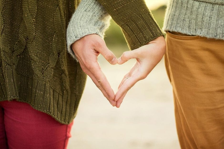 a couple making the heart symbol with their hands
