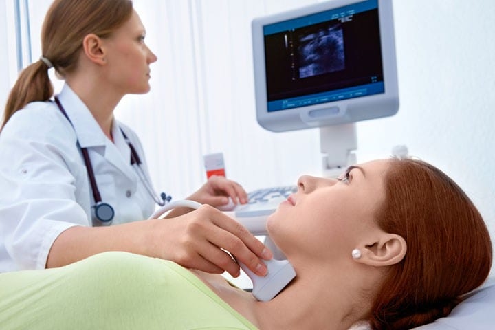 doctor with ultrasound looking at womans thyhroid