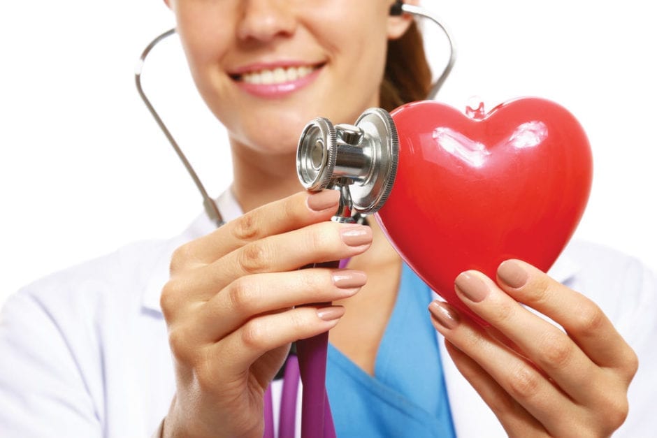 doctor with a stithoscope touching a red toy heart
