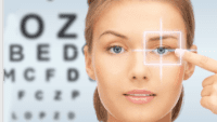ophalmo woman pointing to her eye and an eye testing board behind her