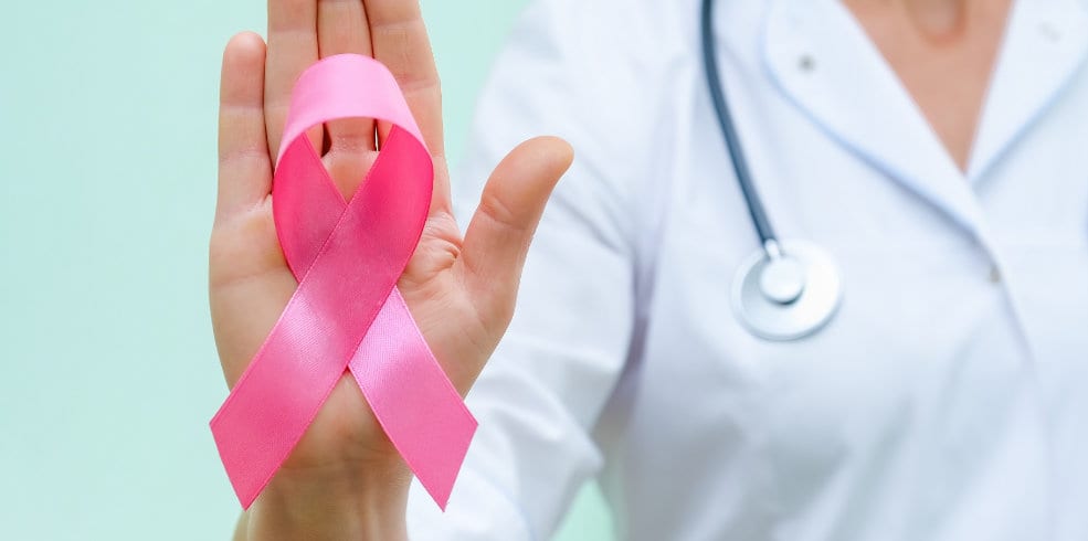 Pink ribbon for breast cancer awareness in doctor's hand, women breast tumor illness campaign.