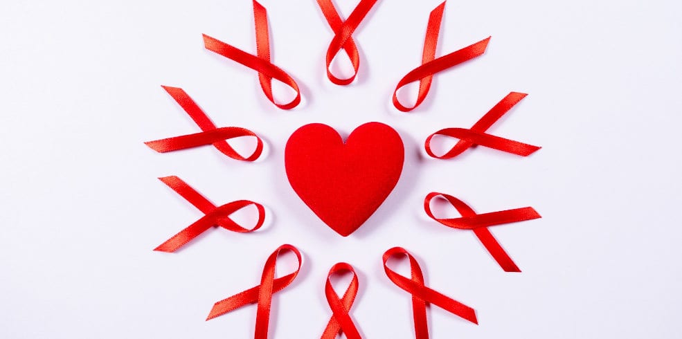 AIDS awareness red ribbon around red heart on red background