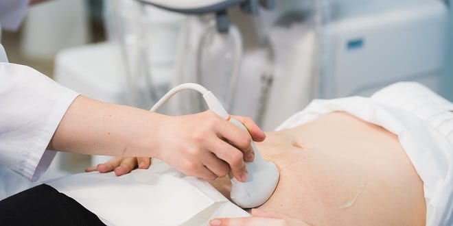Close-up Of Doctor Moving Ultrasound Probe On Pregnant Woman's Stomach In Hospital.